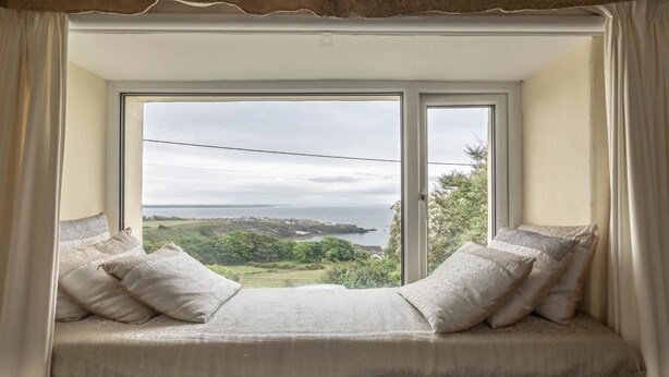 Ein Zimmer mit einem großen Erkerfenster mit Blick auf eine reizvolle Landschaft.