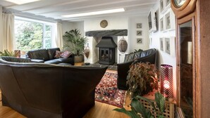 Ein gemütliches Wohnzimmer mit Kamin, Ledersofas und einer großen Wanduhr.