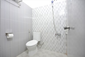 A bathroom with a toilet, a shower, and a tiled wall. - OYO 1303 Golden Inn 2 (Yogyakarta)