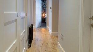 Un couloir étroit avec un plancher en bois et des murs blancs.