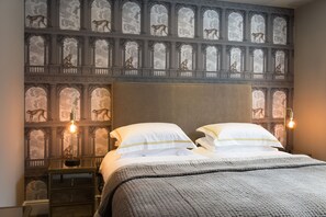 A bedroom with a large bed, two nightstands, a wall with a mural of monkeys, and a modern light fixture. - Belford (Harrogate)