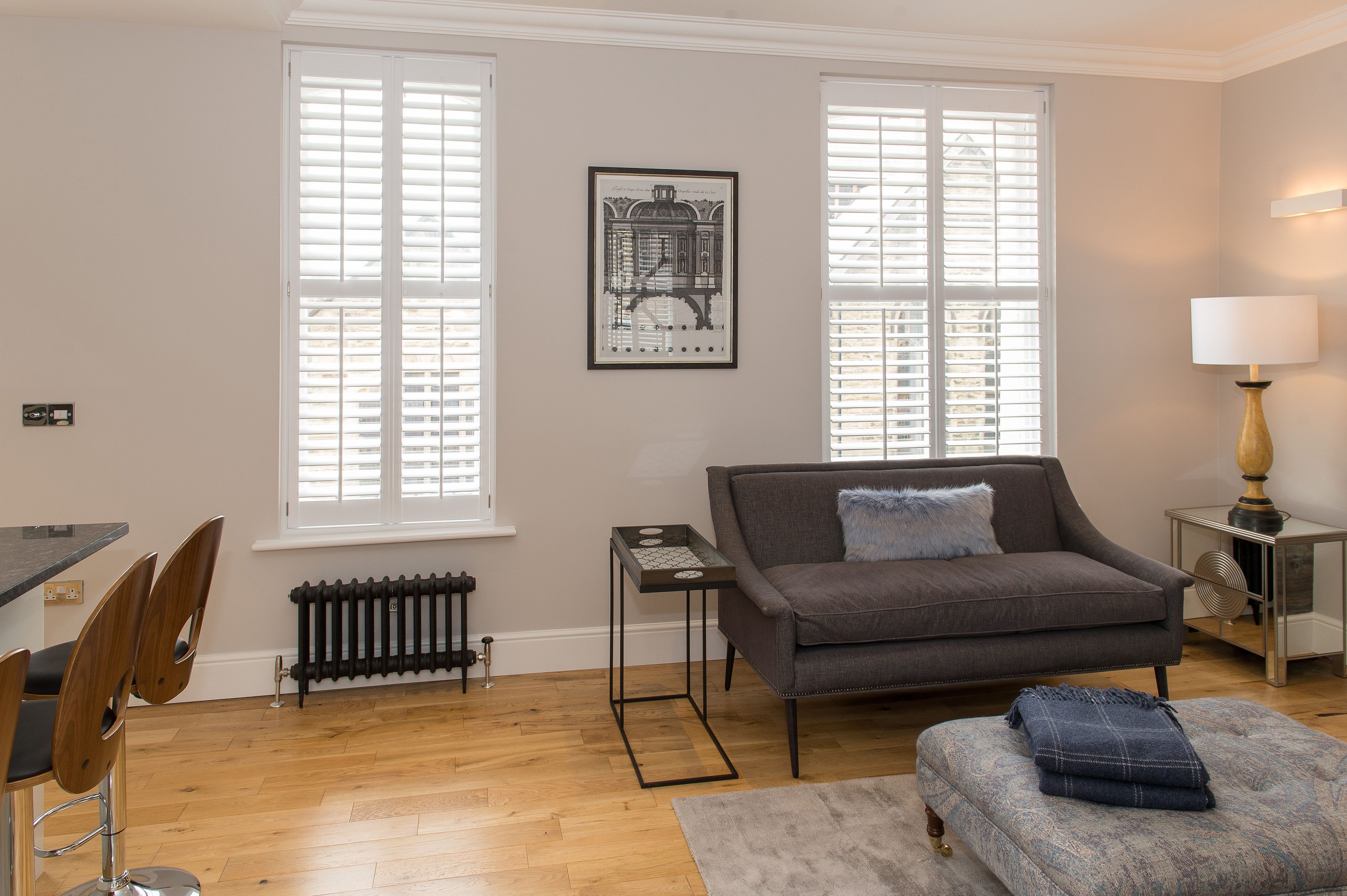 A living room with a grey sofa, a small table, and a radiator.