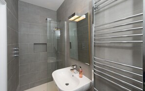 A modern bathroom with a glass-enclosed shower, a white sink, and a large mirror. - Belford (Harrogate)