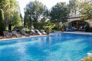 A swimming pool with lounge chairs, a patio area, and a stone building with a tiled roof. - Mas au Coeur de la Provence - Chambres d'hotes (Saint-Cannat)