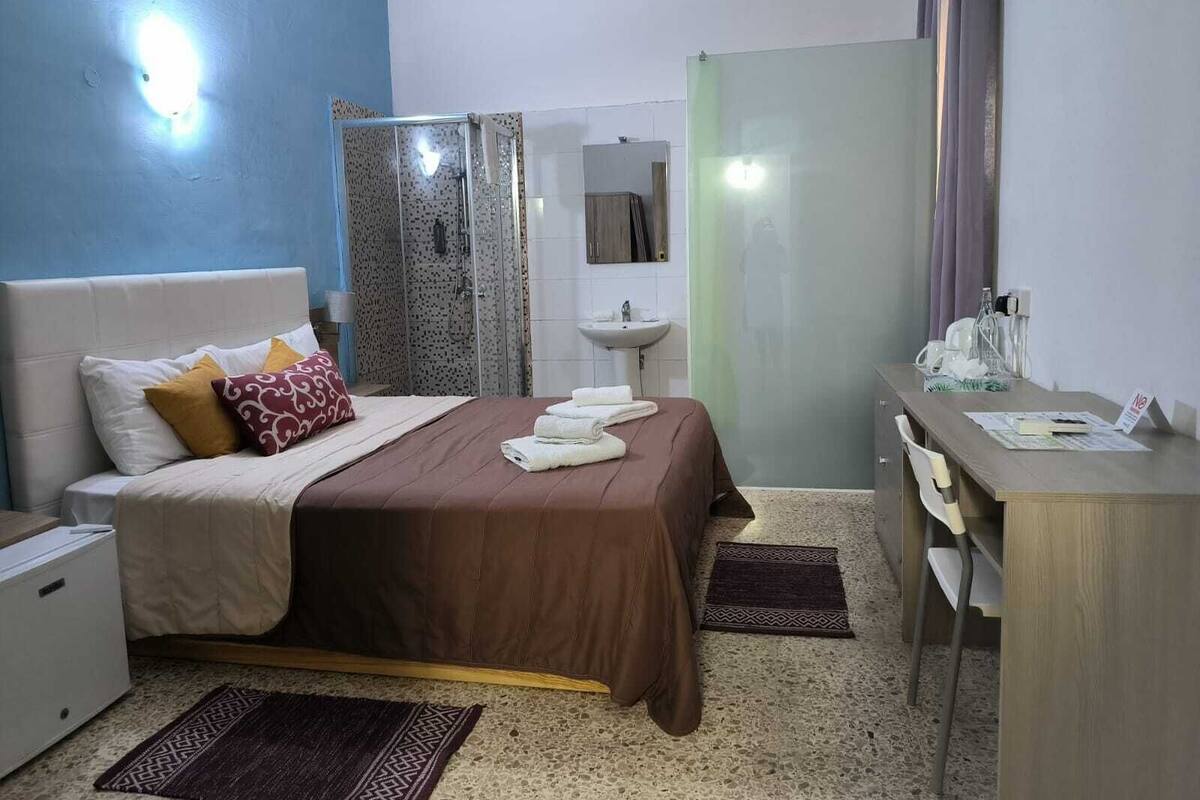 Une chambre d’hôtel comprenant un lit, une table de chevet, un bureau et un espace douche.
