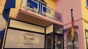 A building with a sign for 'Tarona Guesthouse' and a balcony with railings.