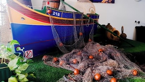 A model boat with a fishing net and buoys, a 'No Smoking' sign, and a scenic coastal photograph on the wall.