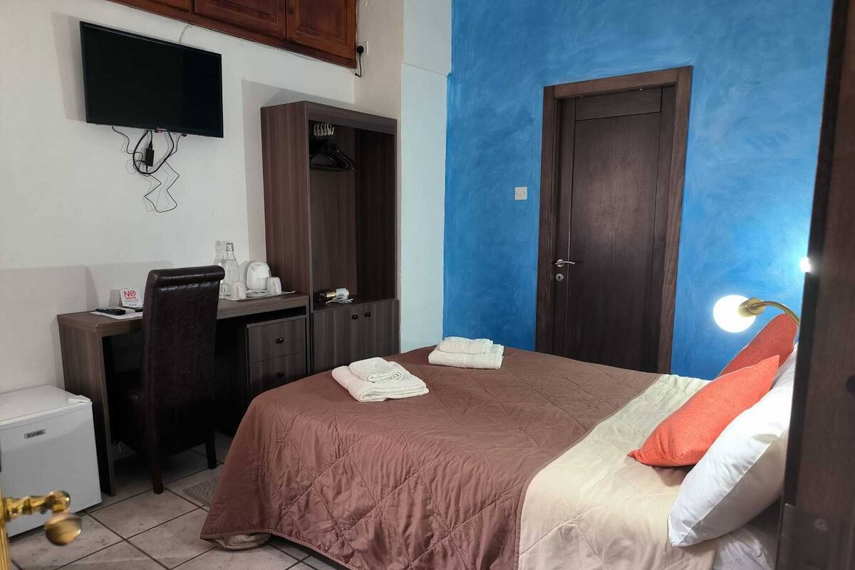 Une chambre à coucher comprenant un lit, un bureau, une armoire, une télévision et une salle de bain.