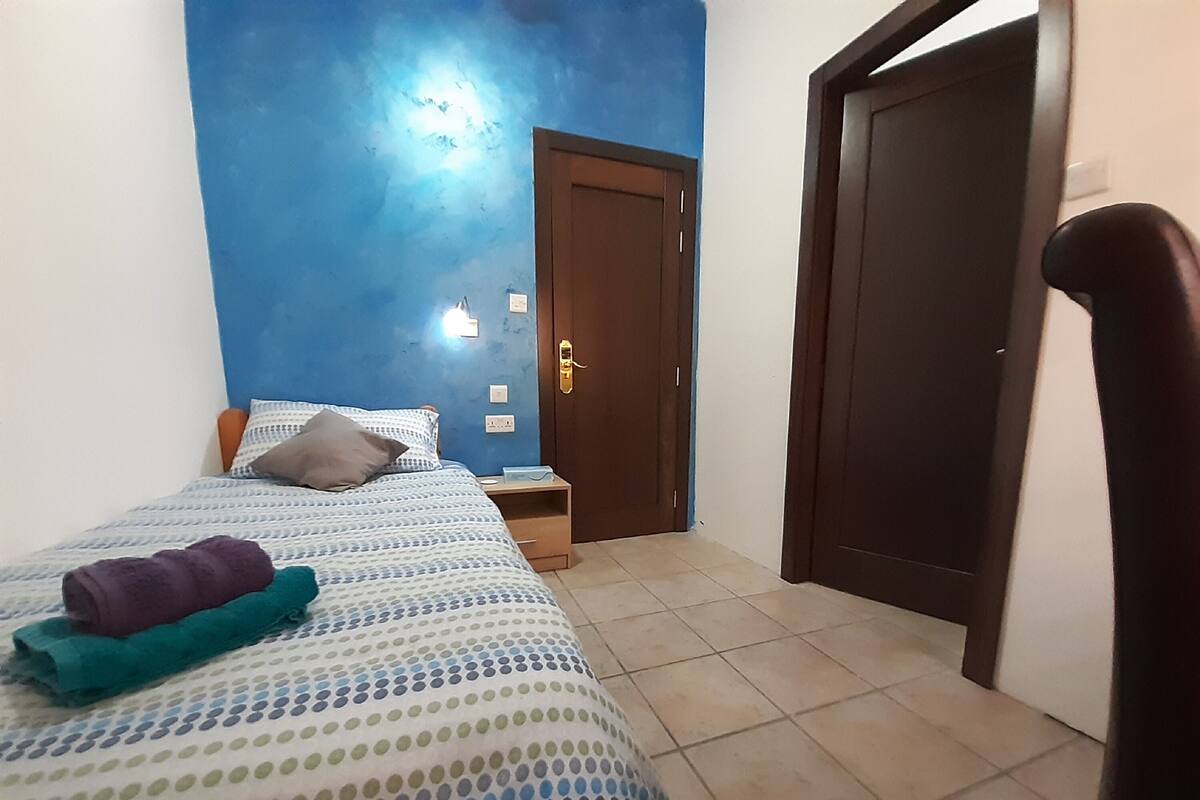 Une chambre à coucher avec un lit, une table de chevet, une porte et une chaise.