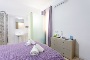 Un dormitorio con cama, cómoda, espejo, lavabo y zona de ducha.