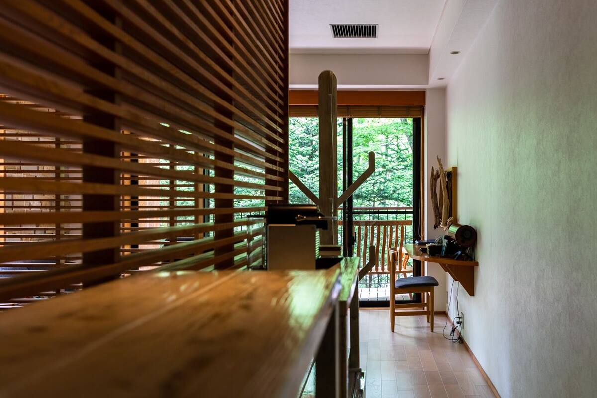 A modern interior with a wooden slatted partition, a cactus sculpture, and a view of greenery through large windows.