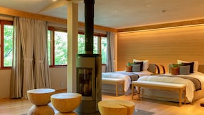A modern bedroom with a central wood-burning stove, two beds, and a large window with curtains. - Ancient Hotel asama karuizawa (Karuizawa)