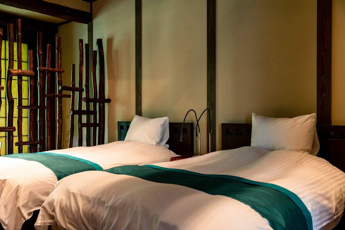 A hotel room with two beds, wooden headboards, and a window with a view.