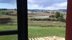A view from a window overlooking a rural landscape with fields, a pond, and distant hills. - Al Dolce Farniente (Marsciano)