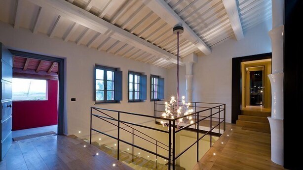 A spacious interior with a high ceiling, wooden flooring, and a central staircase with a railing. - Al Dolce Farniente (Marsciano)