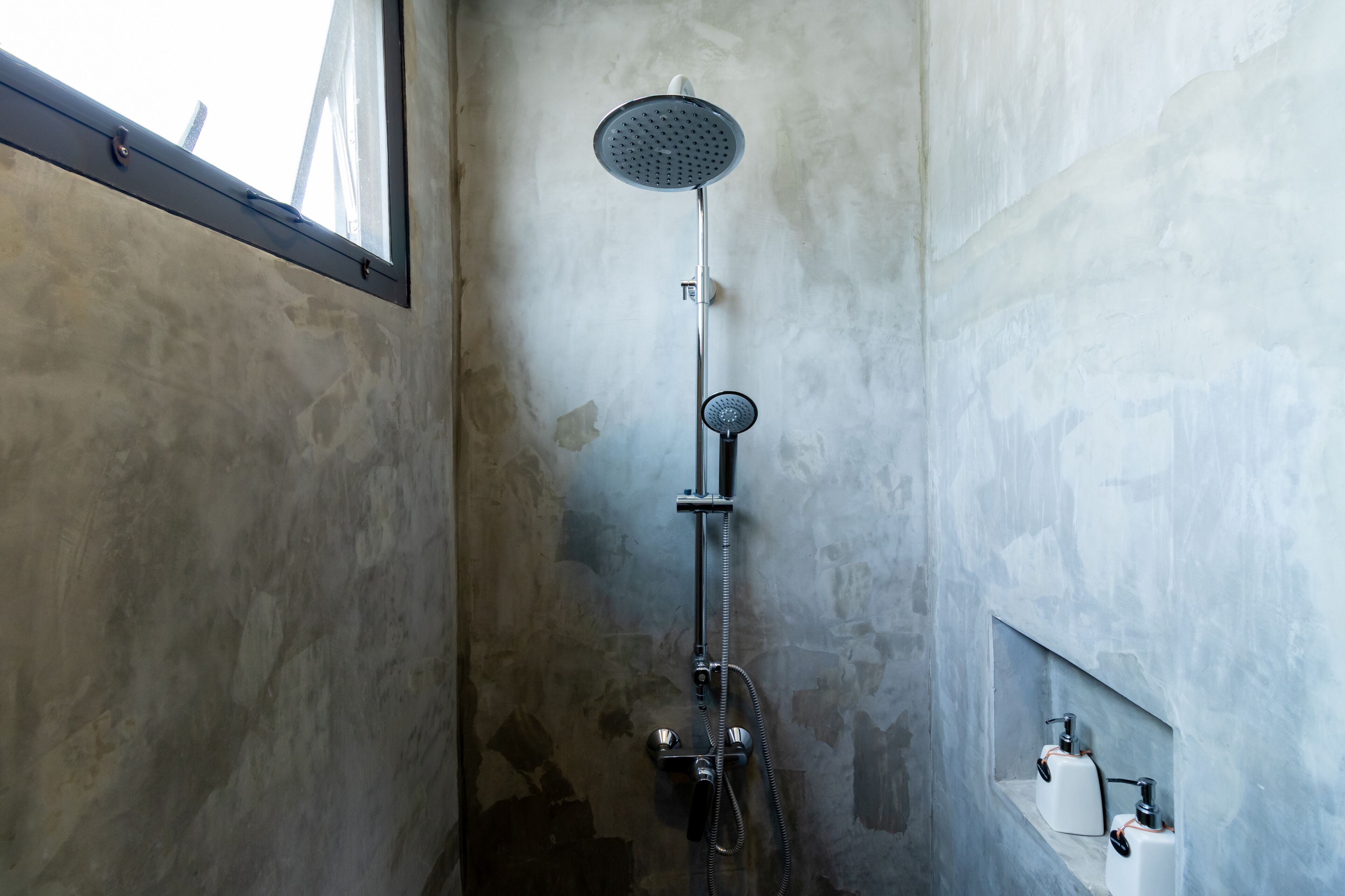 A shower with a handheld showerhead and a wall-mounted faucet.