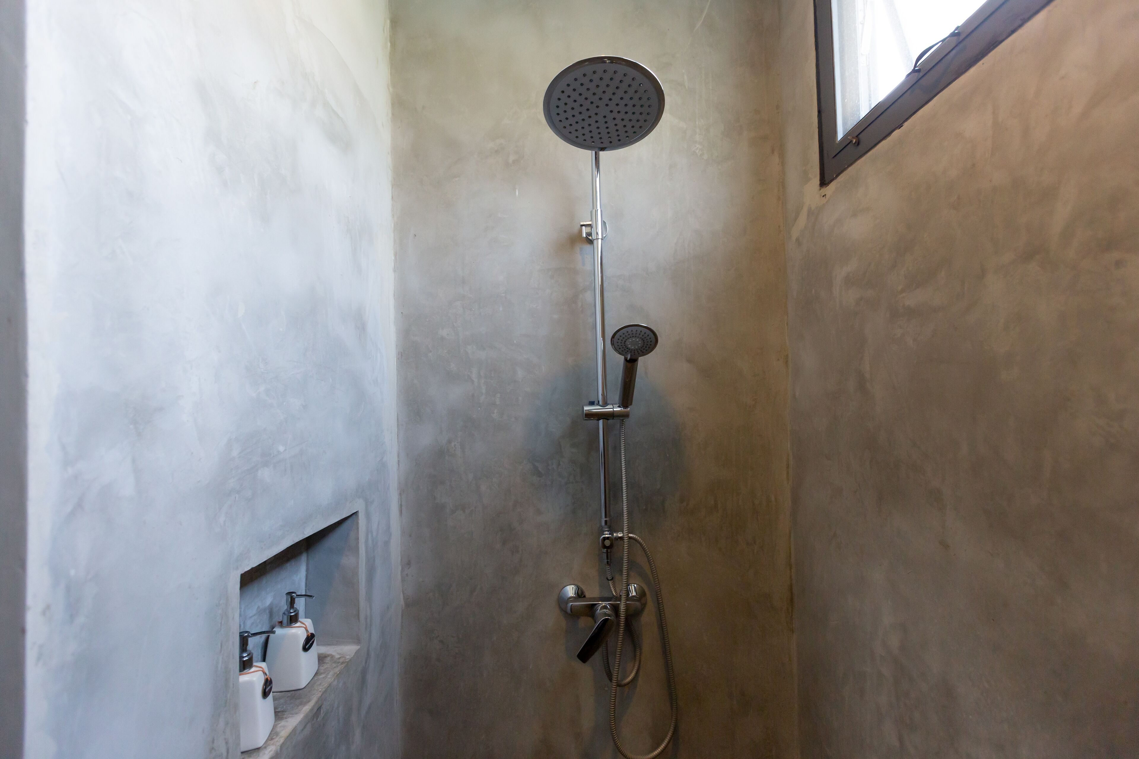 Ducha con cabezal de ducha de mano y llave incorporada a la pared.