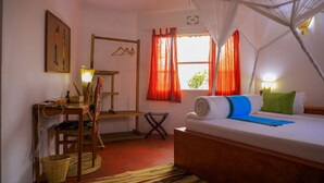 Un dormitorio con cama, escritorio, silla, perchero y ventana con cortinas.