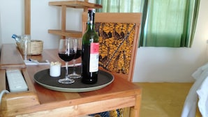 A wooden table with a bottle of wine, two glasses, and a remote control. - Dan Stam Hotel (Arusha)
