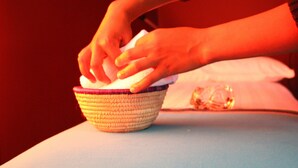 Una persona colocando un paño blanco en una cesta tejida sobre una mesa.