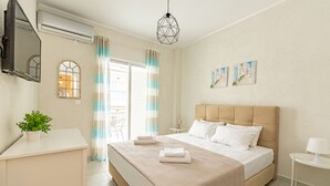 A modern bedroom with a large bed, a bedside table, a small table, a potted plant, and a window with curtains. - Kordela studios (Kassandra)