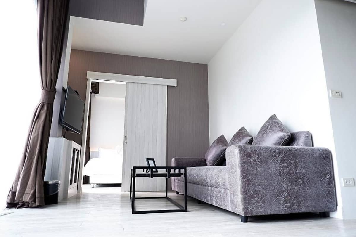 Una sala de estar moderna con un sofá gris, una mesa de centro negra y un televisor montado en la pared.