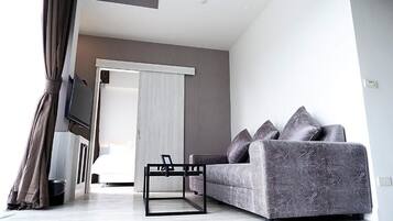 Una sala de estar moderna con un sofá gris, una mesa de centro negra y un televisor montado en la pared.