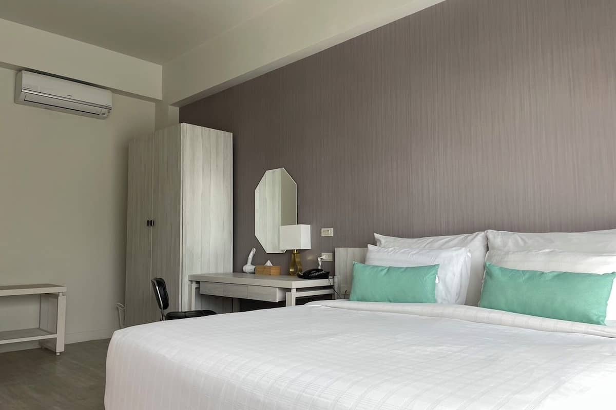 Una habitación de hotel con una cama grande, un escritorio con lámpara, un espejo y un armario.