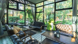 Una sala de estar moderna con ventanas amplias, sofás de cuero y una estatua de rana verde.