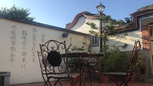 A patio with a table and chairs, a wall with Chinese characters, and a street lamp. - Love nostalgia No. 53 B&B (Jincheng)