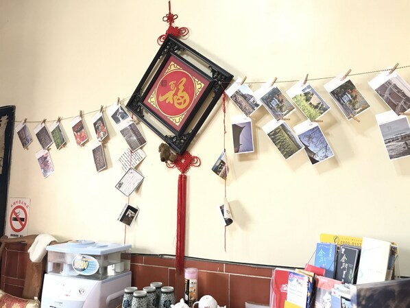 Un mur décoré d’un motif constitué d’un caractère chinois rouge, une guirlande de photos et un distributeur d’eau.