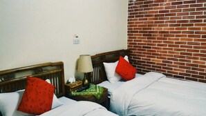 A hotel room with two beds, a nightstand with a lamp, and a brick wall. - Love nostalgia No. 53 B&B (Jincheng)