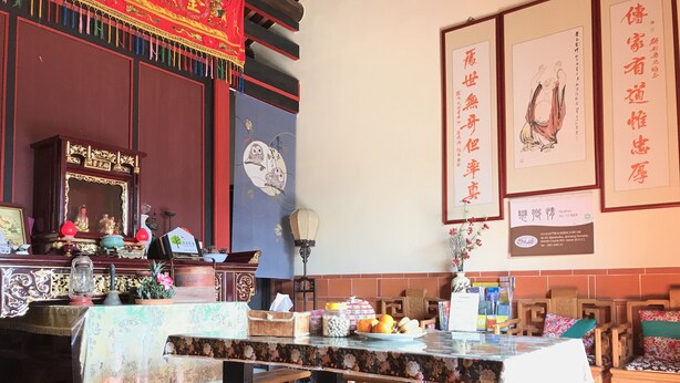 A traditional Chinese room with a wooden altar, a table with a floral tablecloth, and several framed artworks on the walls. - Love nostalgia No. 53 B&B (Jincheng)