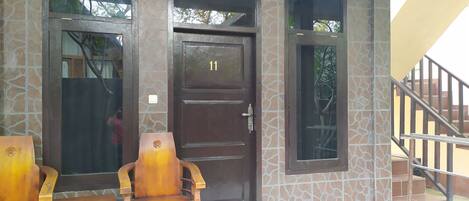 A building entrance with a dark brown door marked with the number 11, a small window, and a staircase leading to an upper level.