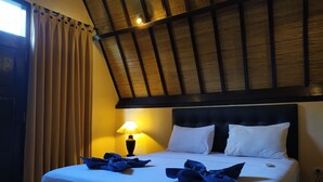 A hotel room with a bed, a lamp, and curtains.