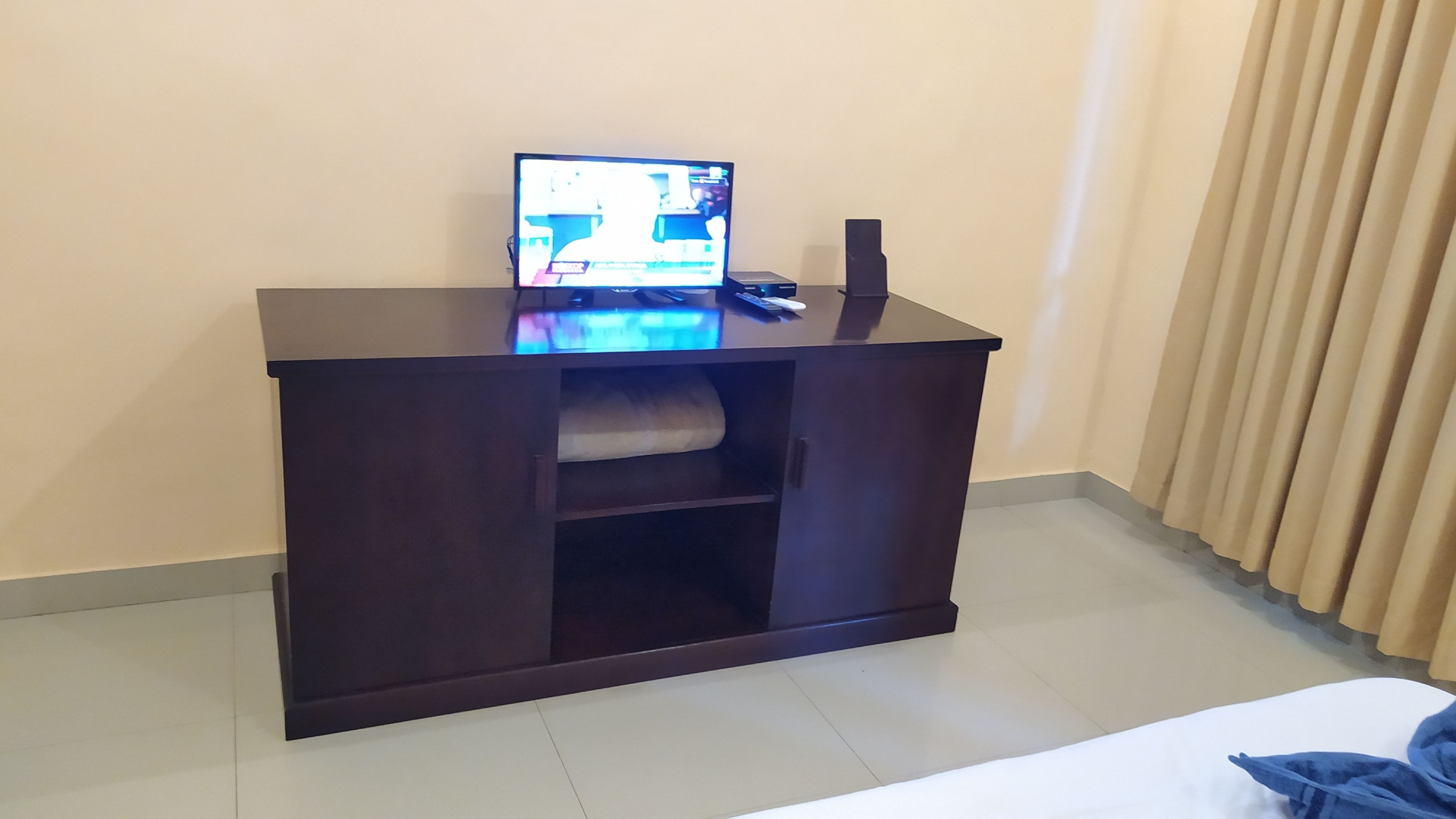 Un escritorio de madera oscura con una computadora portátil, un control remoto y un altavoz.