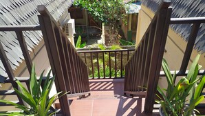A gated entrance to a balcony with potted plants on either side.
