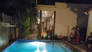 A rectangular swimming pool with a clear blue water surface, surrounded by a low stone wall.