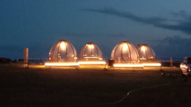 Three dome-shaped structures with illuminated interiors, set in an open field at dusk. - Han Ting B&B (Hualien City)