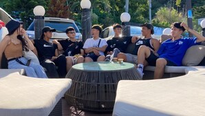 A group of people sitting around a round table with a glass top, under a large umbrella, with a mountainous landscape in the background. - Han Ting B&B (Hualien City)