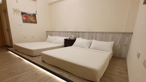 A hotel room with two single beds, a wooden floor, a nightstand with a lamp, and a painting on the wall. - Han Ting B&B (Hualien City)