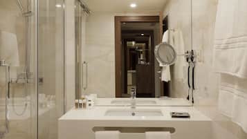 Un bagno moderno con doccia vetro, due lavabi, uno specchio e un porta asciugamani.