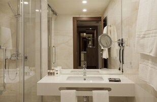 Un bagno moderno con doccia vetro, due lavabi, uno specchio e un porta asciugamani.