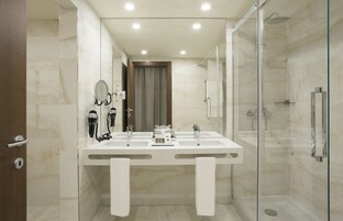 A modern bathroom with a glass-enclosed shower, a double sink vanity, and a large mirror.
