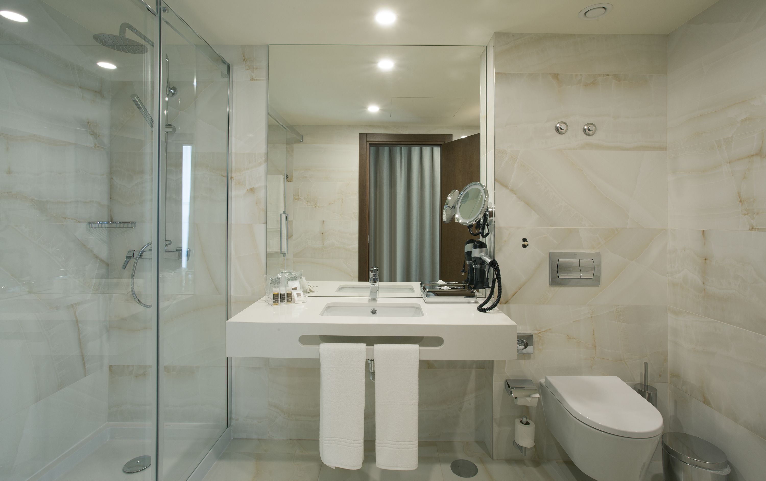 A modern bathroom with a glass shower enclosure, a white sink with a mirror, and a toilet.