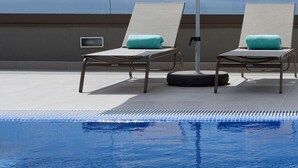 A poolside area with two lounge chairs and a large umbrella, overlooking a clear blue sky and a distant view. - Madeira Turim Santa Maria Hotel (Funchal)