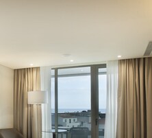 Et hotelværelse med et stort vindue, en sofa, et bord og en lampe.