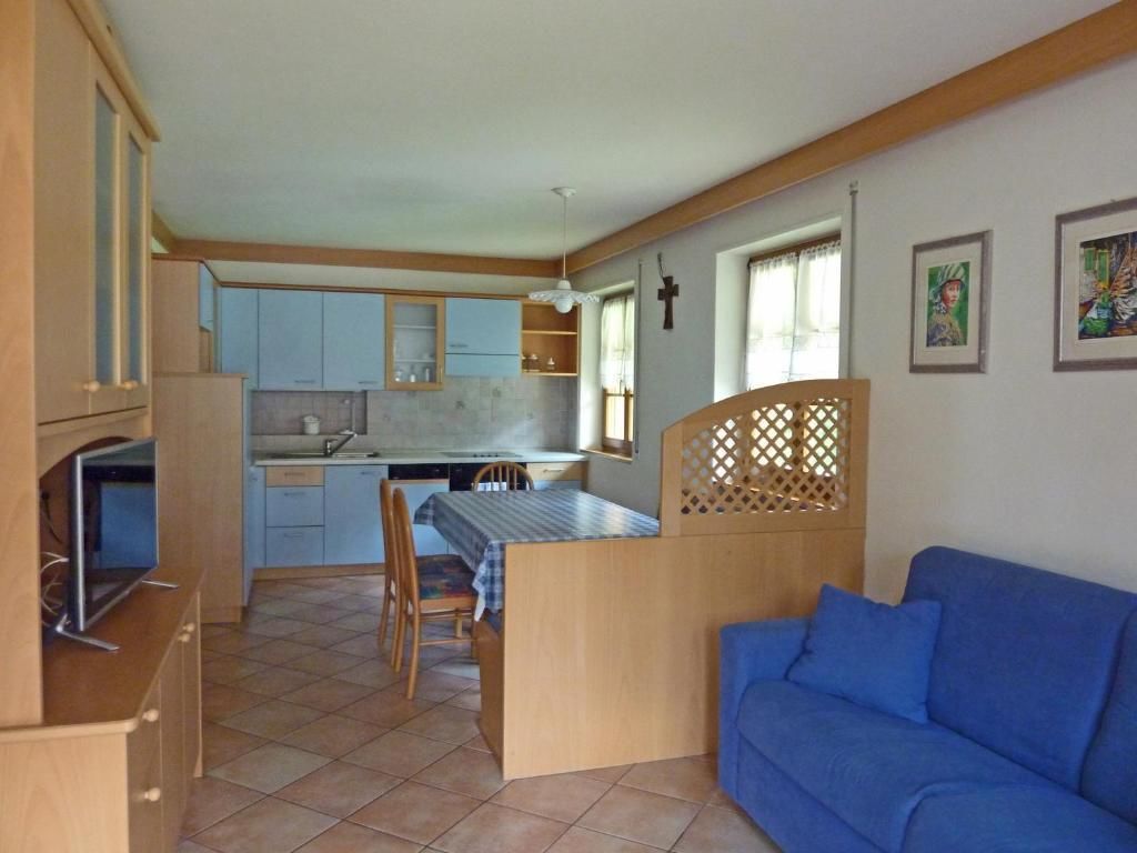 Un espacio habitable compacto con kitchenette, comedor y un sofá azul.
