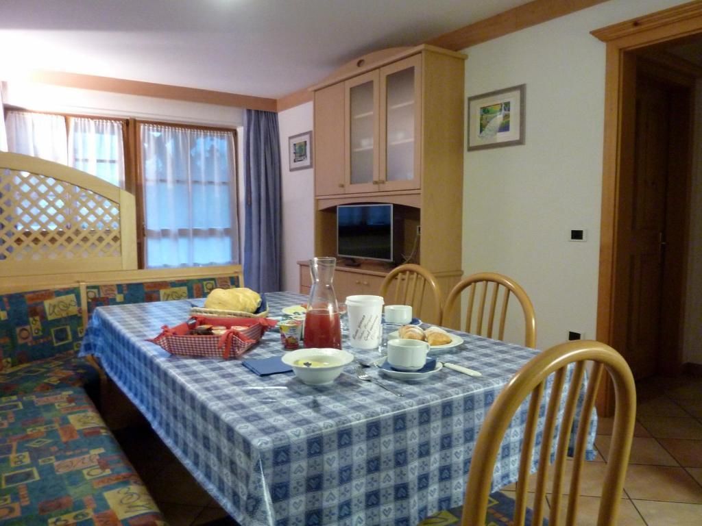 A dining area with a table set for two, a television, and a cabinet above it.