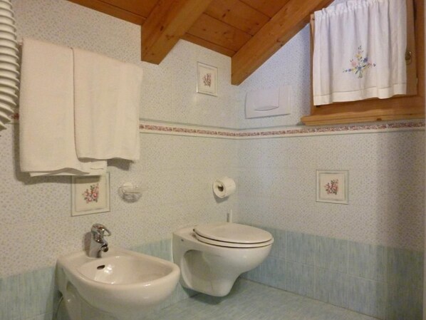 Un baño con lavamanos, inodoro y una toalla colgada en la pared.